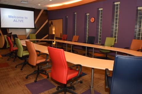 DIRECT is our largest conference space at AL!VE. It can accommodate as few as 10-12 in a small open oval (as pictured above), up to 25 in a large open oval, up to 80 theater style or approximately 45 set formally for dining. This space rents for $200 for 1/2 day (up to 4 hours) or $300 for full day (up to 8 hours). Room rental includes use of A/V which is built into the infrastructure of the room, projector/screen, microphones, conference calling and video recording capabilities.